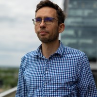 Michał Piądłowski wearing glasses standing outdoors near an office building